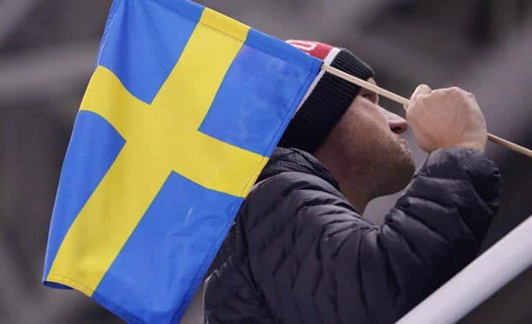 En man som håller en svensk flagga vid en fotbollsmatch